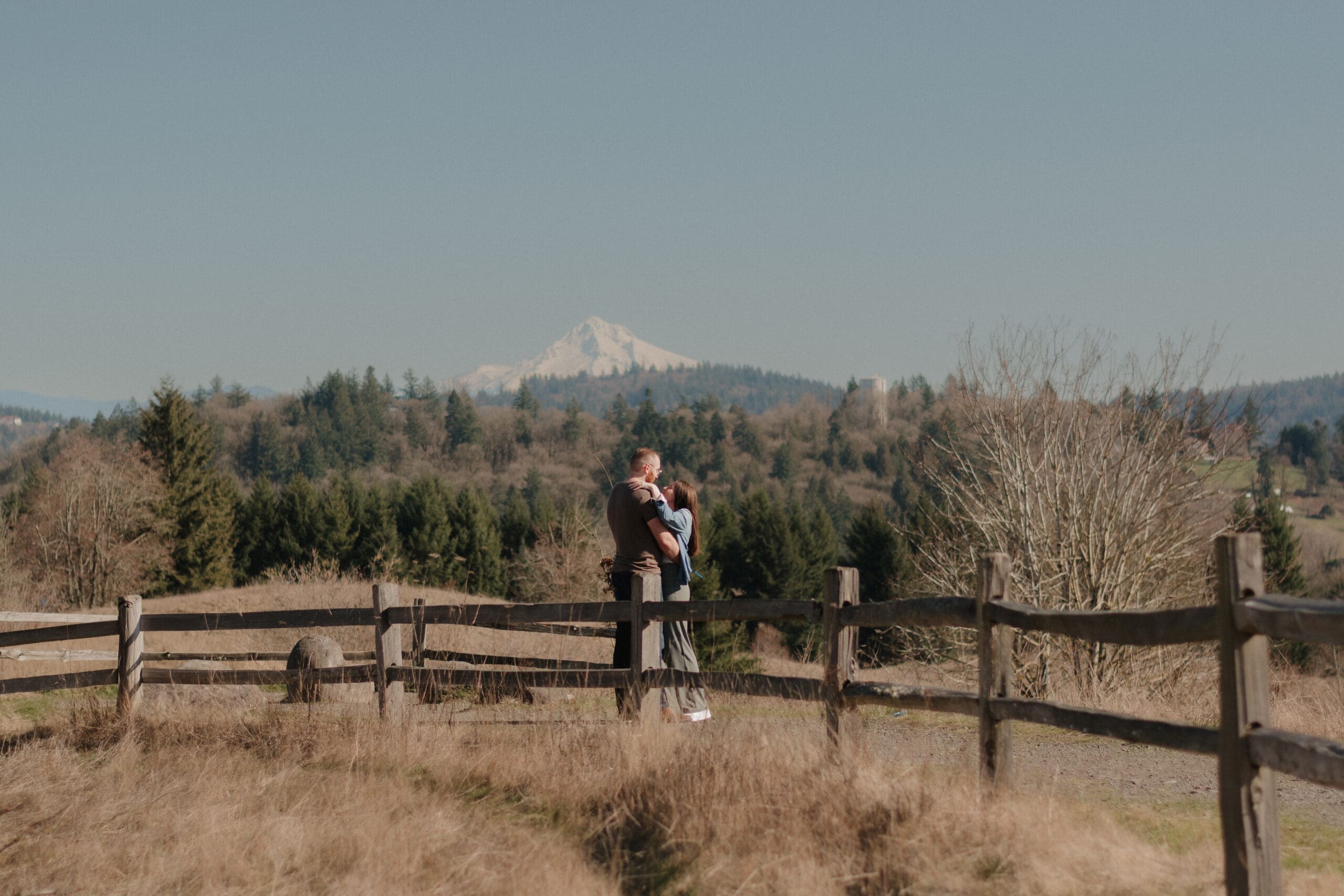 A couple embracing on top of Powell Butte in front of Mount Hood