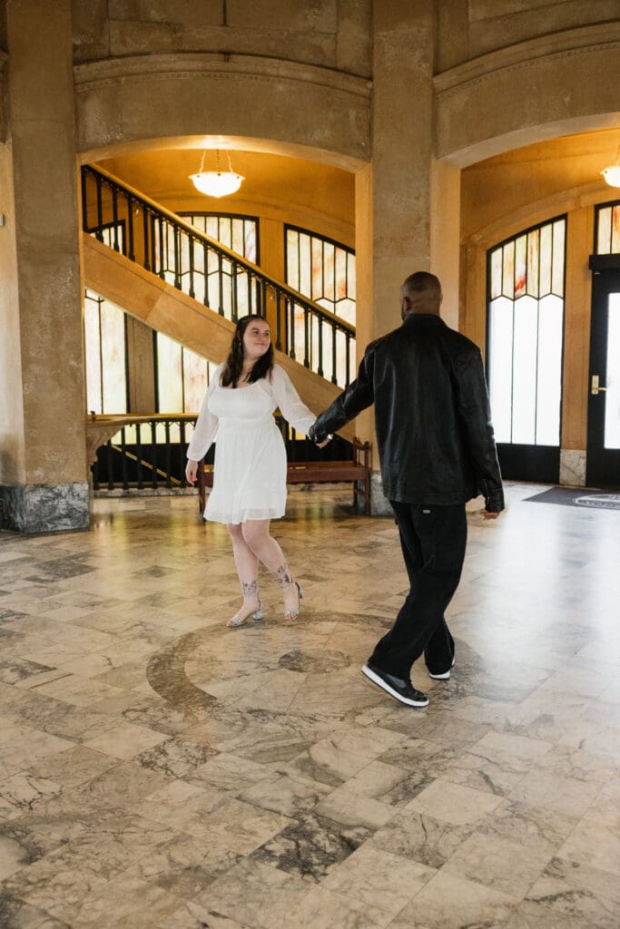 Couple holding hands beneath marble columns inside Vista House at Crown Point in Corbett, Oregon.