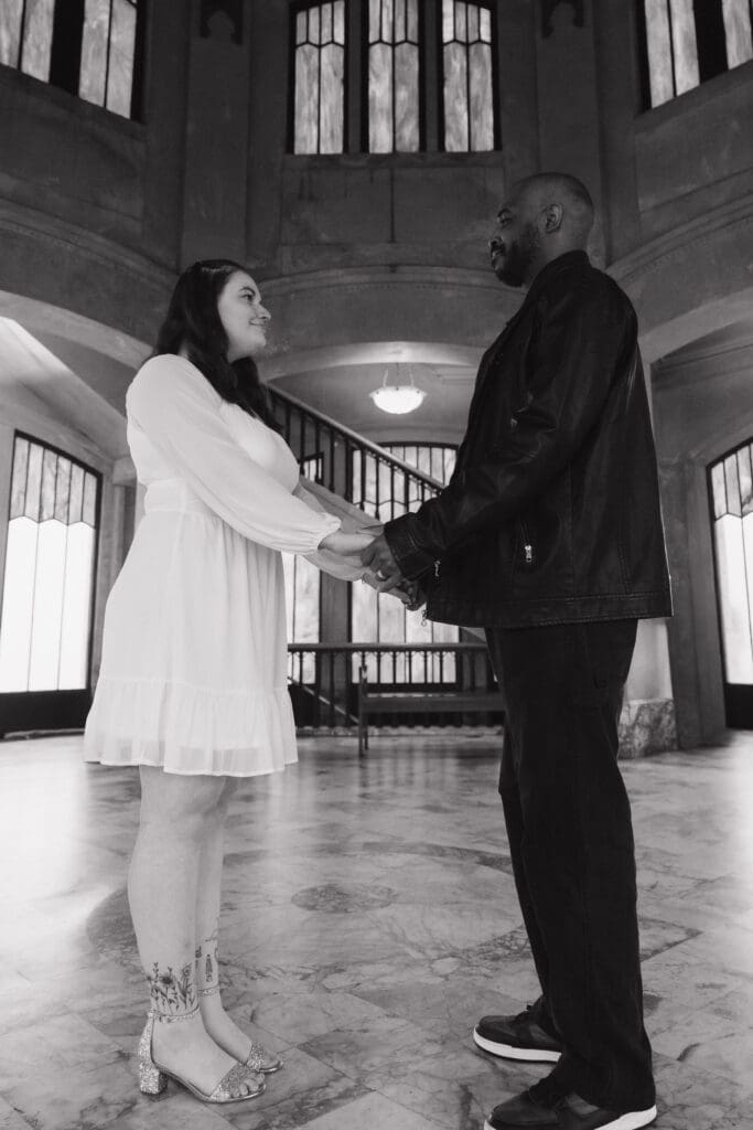 Black and white portrait of couple holding hands inside Vista House at Crown Point in Corbett, Oregon.