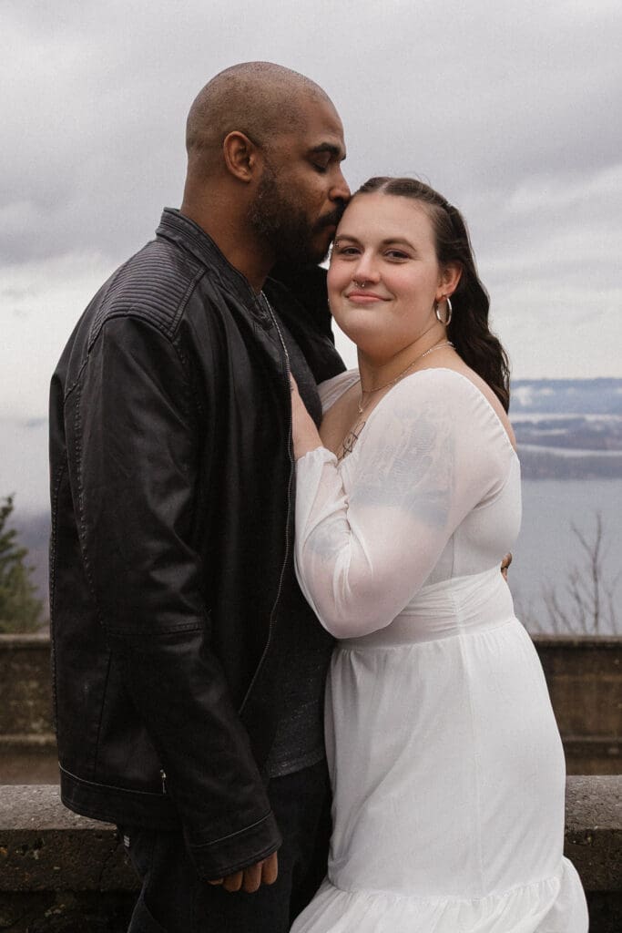 Couple embracing near arched windows inside Vista House at Crown Point in Corbett, Oregon.