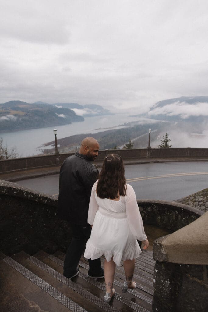 Couple walking down stone steps at Vista House at Crown Point in Corbett, Oregon.