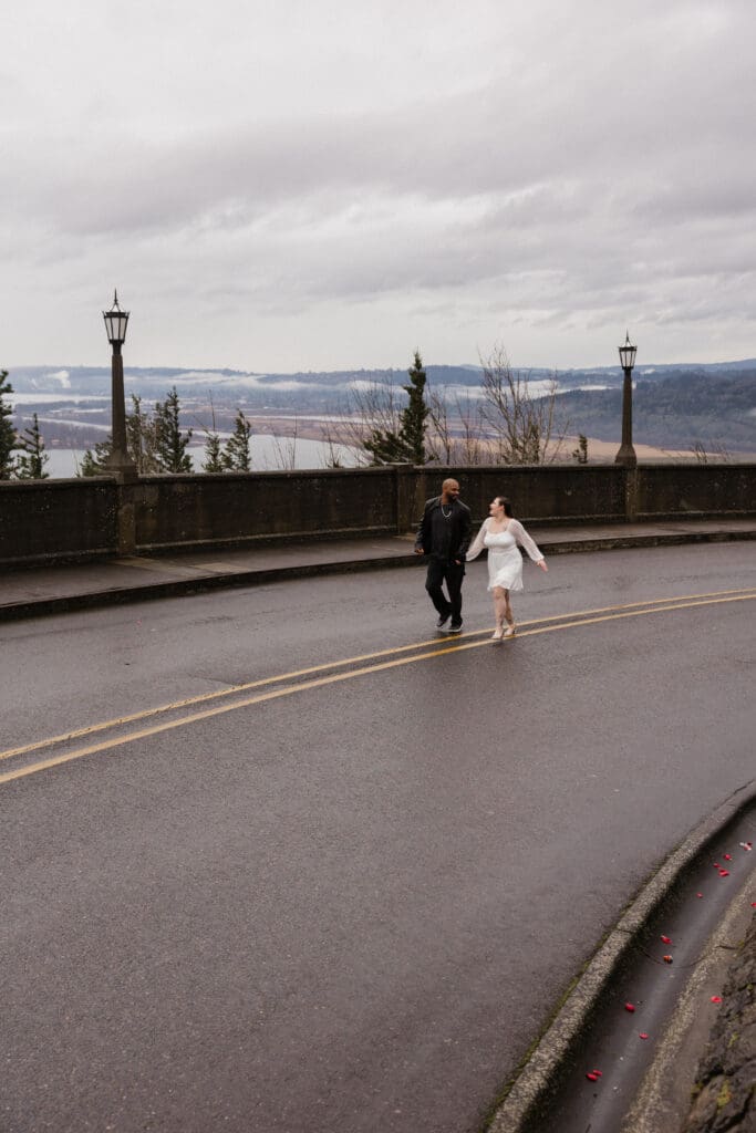 Couple walking along the curved roadway at Vista House at Crown Point in Corbett, Oregon.