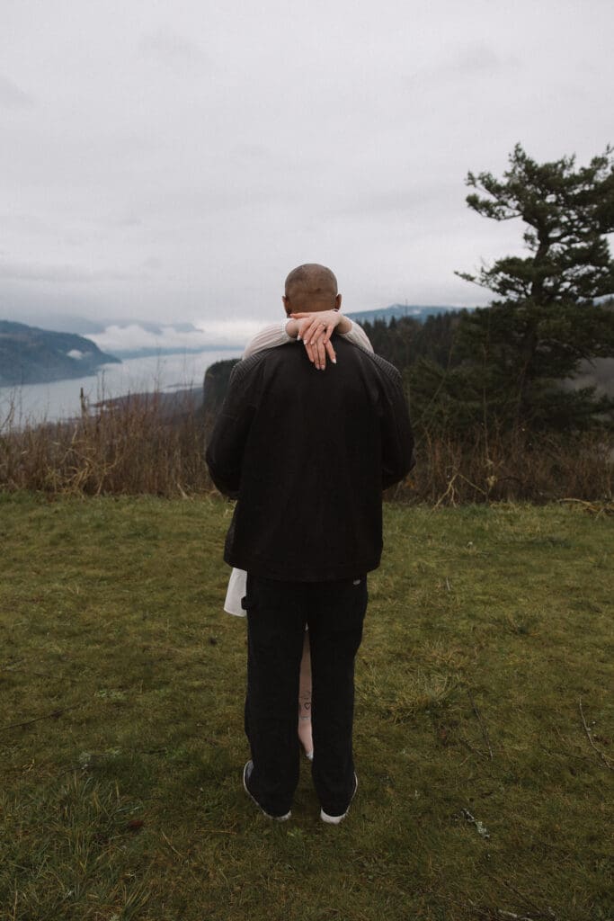 Couple embracing on grassy overlook at Portland Women’s Forum State Scenic Viewpoint in Corbett, Oregon.