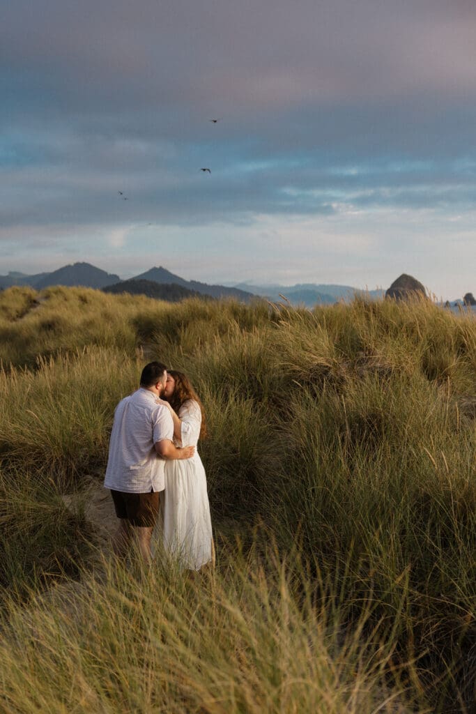 Couple kissing in coastal grass dunes near Portland, Oregon engagement photo locations