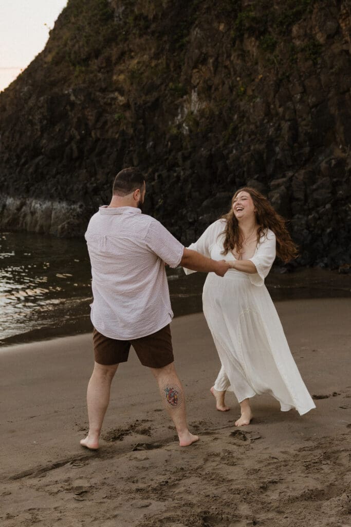 Couple laughing together beside ocean cliffs near Portland, Oregon engagement session location