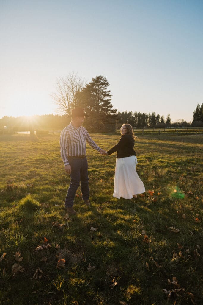 couple holding hands in open field at sunset during engagement session at Champoeg State Park in Oregon