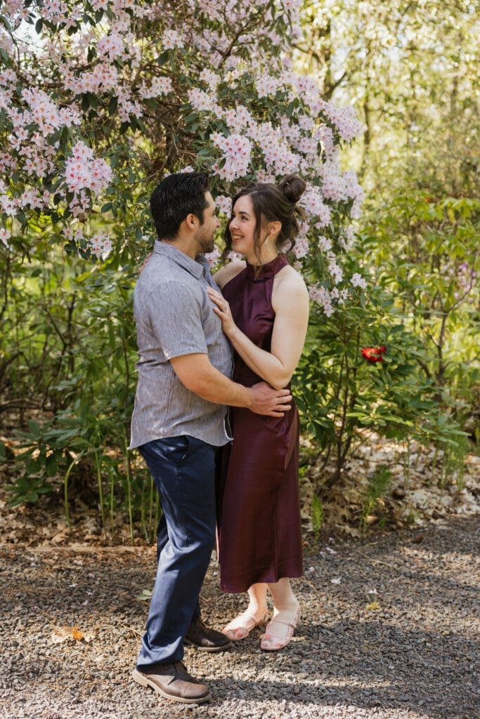 Couple standing beneath blooming flowers at a Portland, Oregon engagement session location