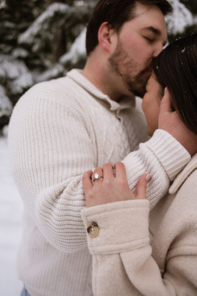 Close-up of engagement ring and couple embracing during snowy Mount Hood engagement photos