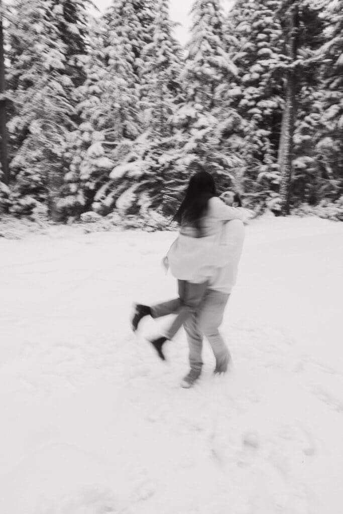 Black and white photo of couple spinning together in the snow near Mount Hood in Oregon
