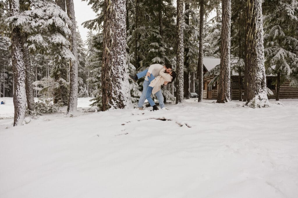 Couple kissing in the snow beside pine trees during a Mount Hood engagement session in Oregon