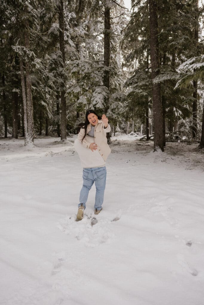 Couple laughing together in a snowy forest during a Mount Hood engagement session in Oregon