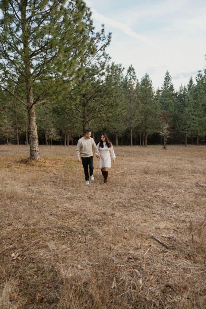 Couple walking through an open pine field near Portland, Oregon for engagement photos