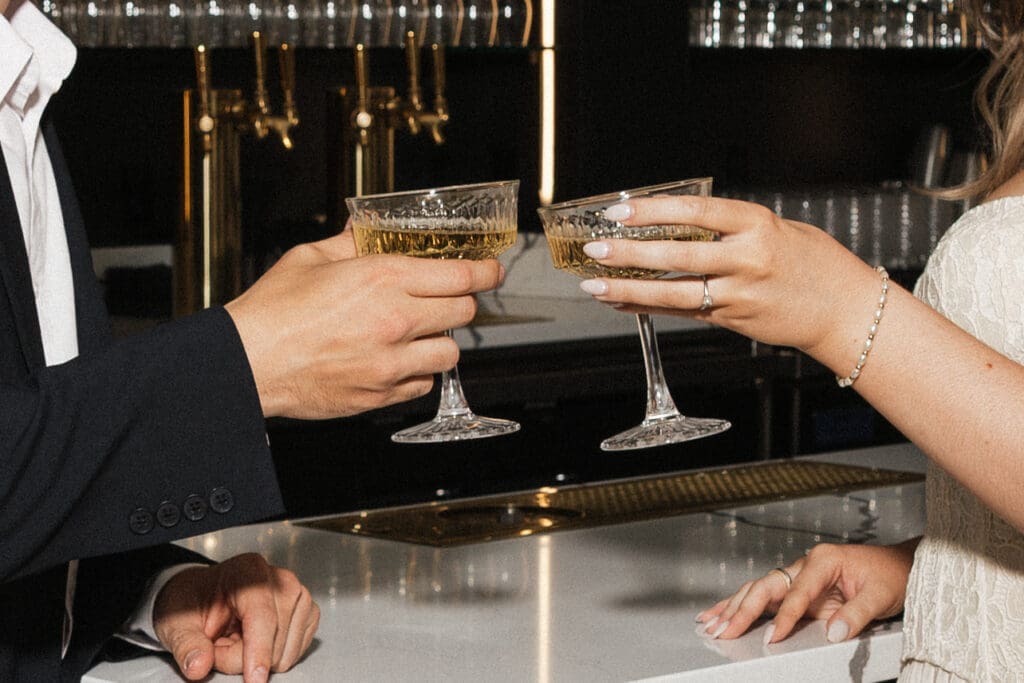 Close-up of couple toasting cocktails during engagement session at The Arc Light in Oregon City, Oregon