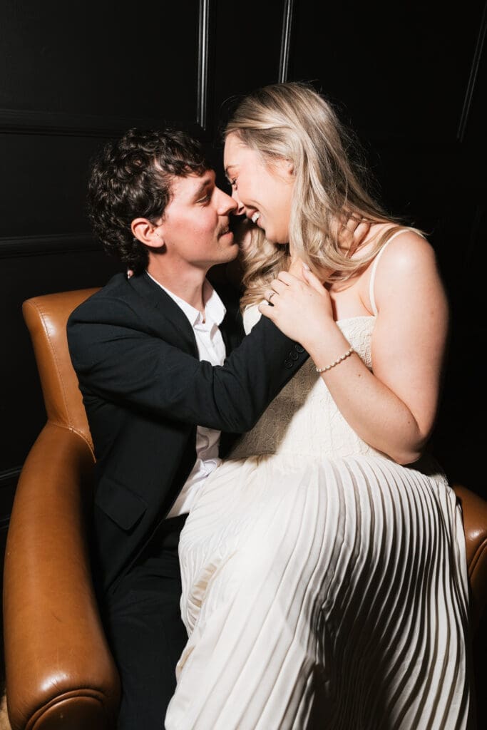 Couple cuddling in a leather chair during engagement photos at The Arc Light in Oregon City, Oregon