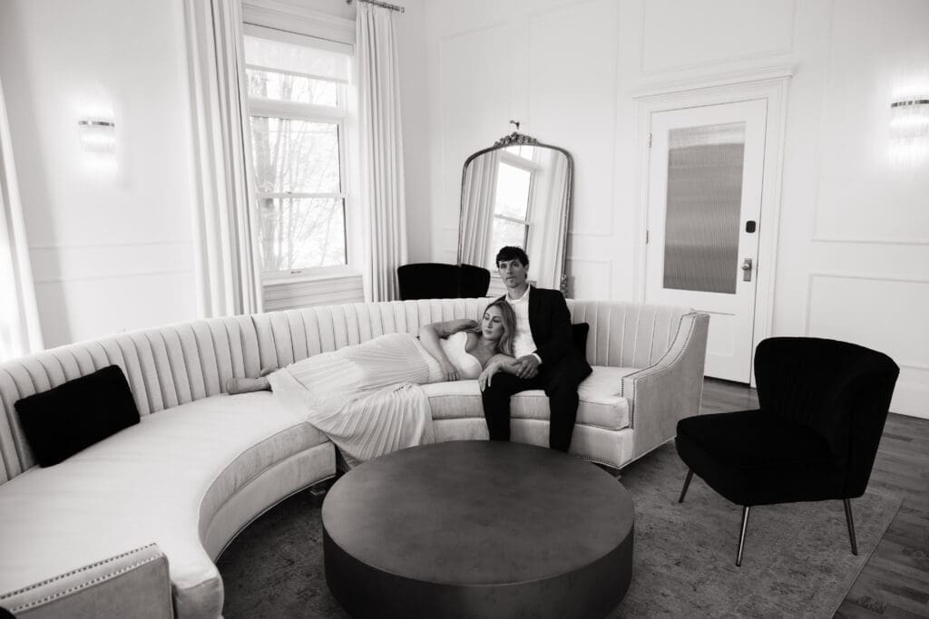Black and white engagement photo of couple relaxing on curved couch at The Arc Light in Oregon City, Oregon