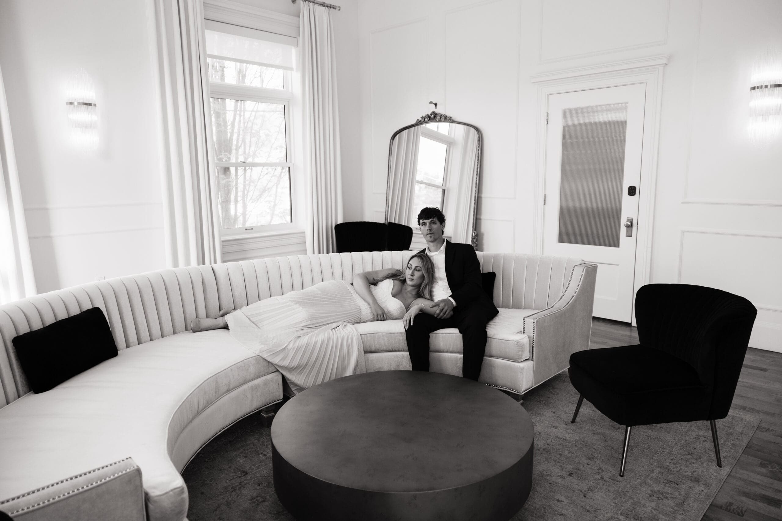 Black and white engagement photo of couple relaxing on curved couch at The Arc Light in Oregon City, Oregon