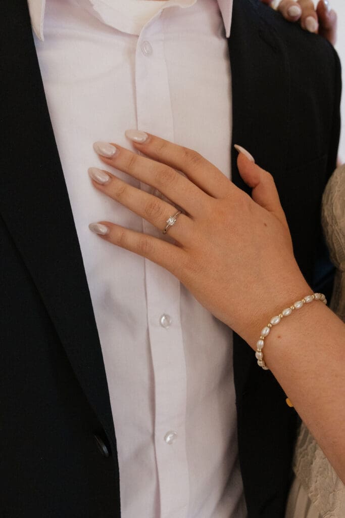 Close-up of engagement ring and hand on black suit at The Arc Light in Oregon City, Oregon