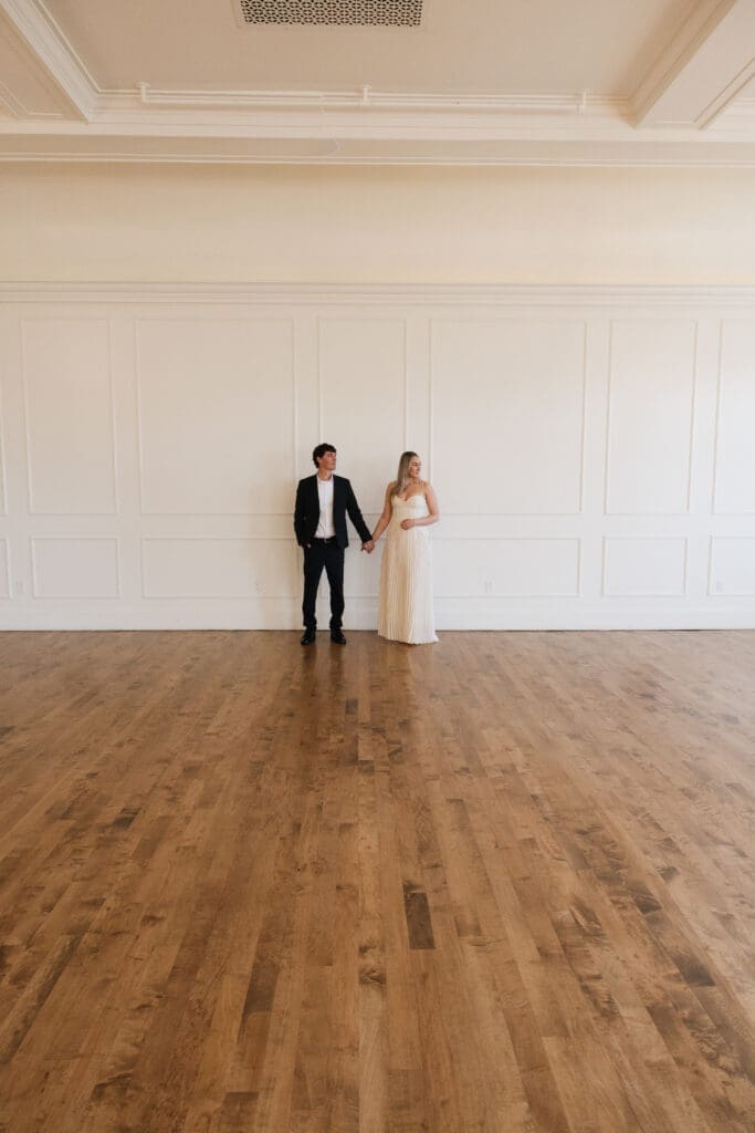 Couple holding hands in bright ballroom at The Arc Light in Oregon City, Oregon