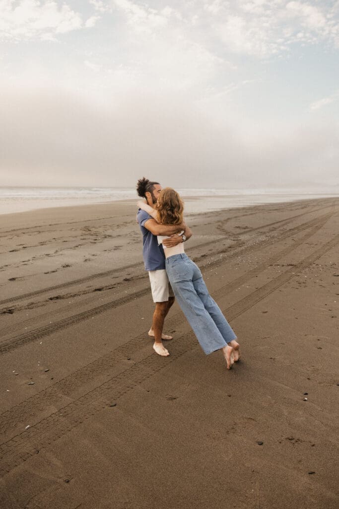 Couple embracing on a quiet beach for Pacific City, Oregon engagement photo inspiration