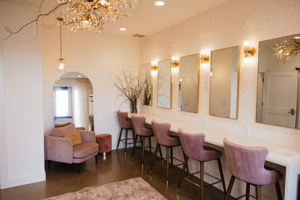 Bright bridal getting ready suite with gold mirrors pink velvet chairs and a crystal chandelier at The Farm on Golden Hill in Silverton Oregon