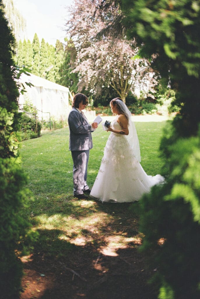 Bride and bride read private vows in the garden during a film wedding at McMenamins Cornelius Pass Roadhouse in Hillsboro, Oregon.