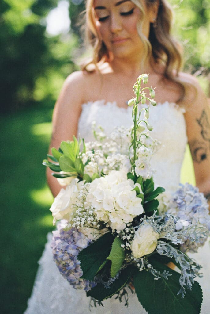 Bride holding a white and blue garden bouquet during a film wedding at McMenamins Cornelius Pass Roadhouse in Hillsboro, Oregon.
