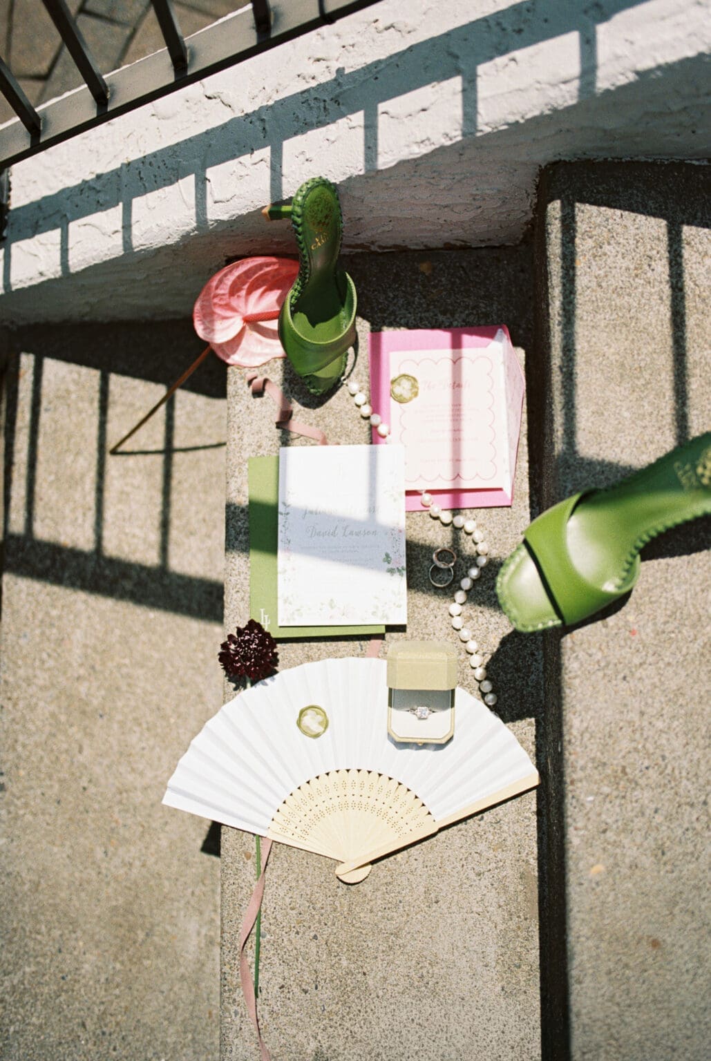 Film photograph of wedding details with invitations, green heels, fan, and rings at Black Walnut Inn in Dundee, Oregon.