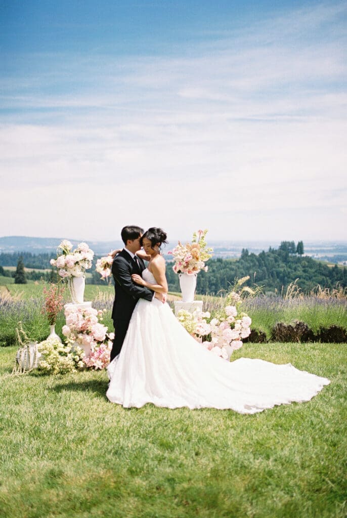 Bride and groom embracing beside floral ceremony arrangements during a film wedding editorial at Black Walnut Inn & Vineyard in Dundee, Oregon.