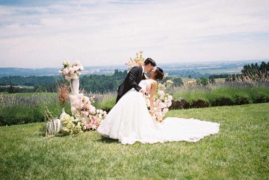 Bride and groom sharing a dip kiss among floral installations during a film wedding editorial at Black Walnut Inn & Vineyard in Dundee, Oregon.