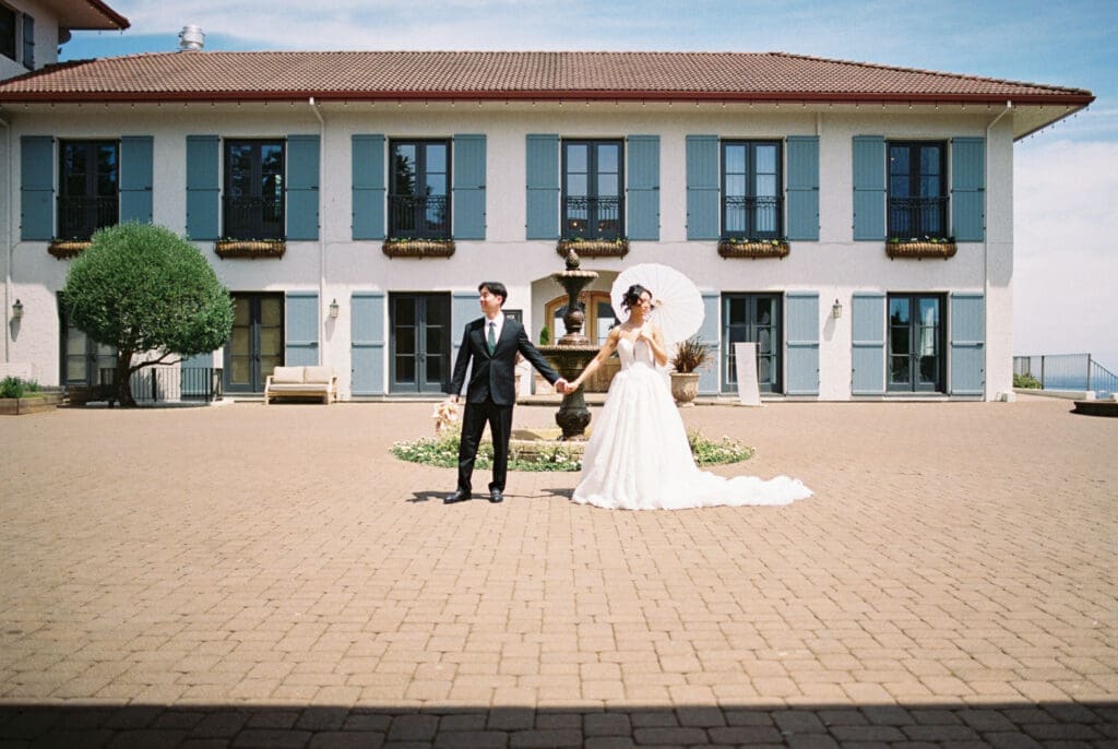 Bride and groom holding hands in the courtyard during a film wedding editorial at Black Walnut Inn & Vineyard in Dundee, Oregon.