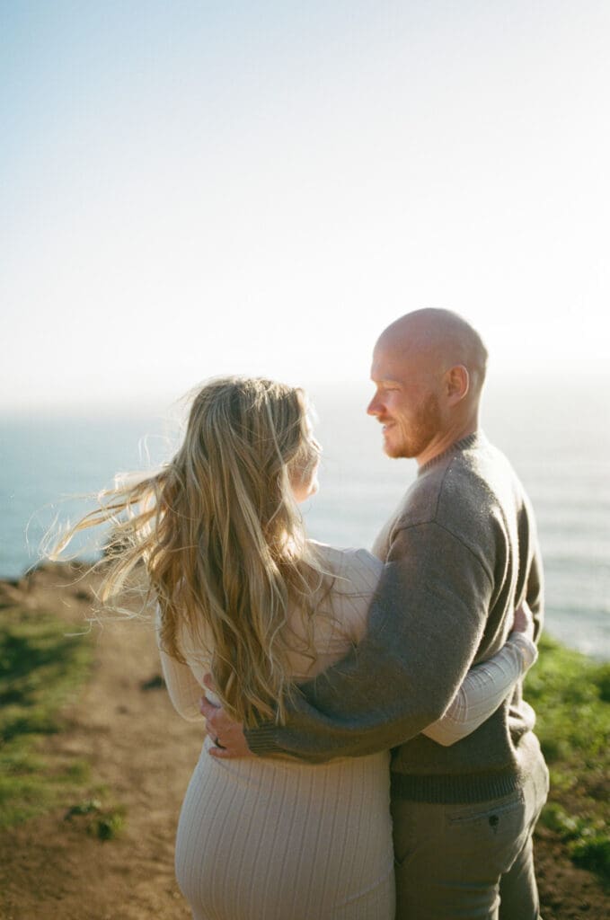 Pregnant couple embracing on a coastal bluff during a film maternity session at Cannon Beach, Oregon.