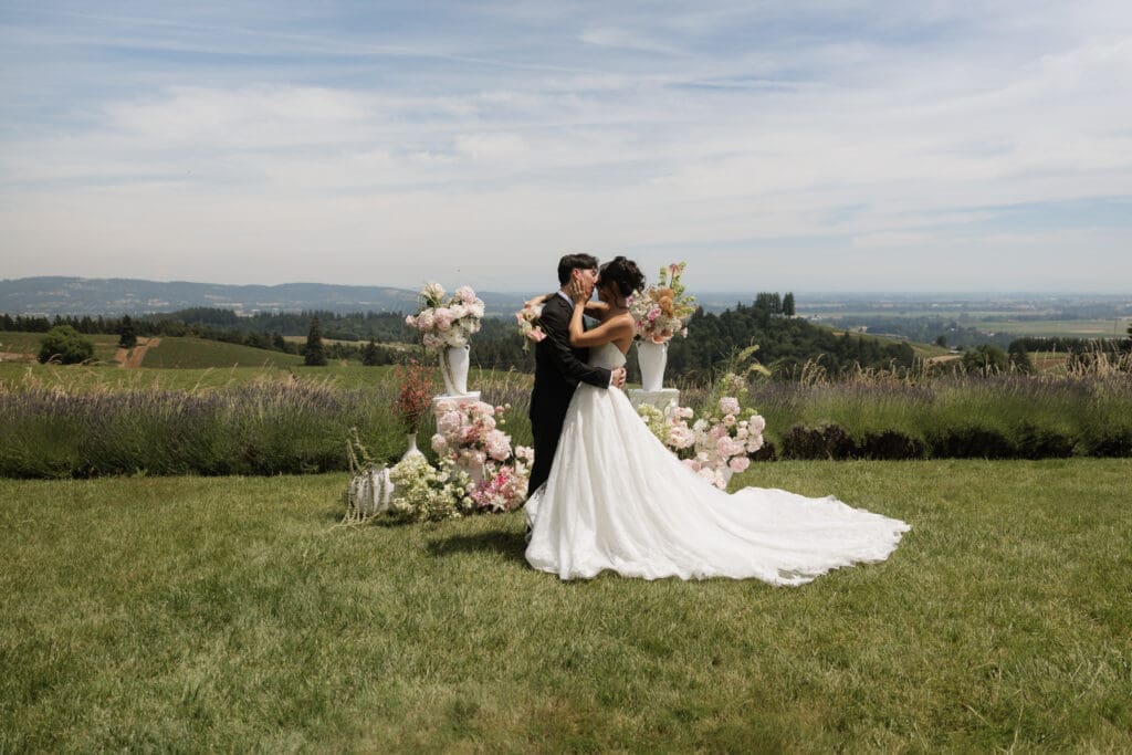 Couple embracing beside floral ceremony arrangements at Black Walnut Inn in Dundee, Oregon vineyard.