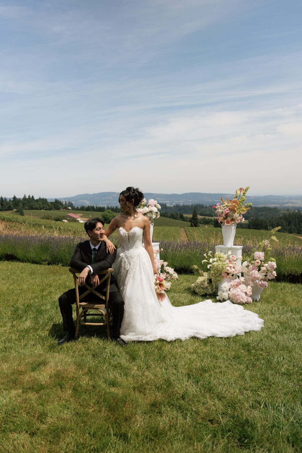 Couple posing with floral ceremony installation overlooking vineyards at Black Walnut Inn in Dundee, Oregon.