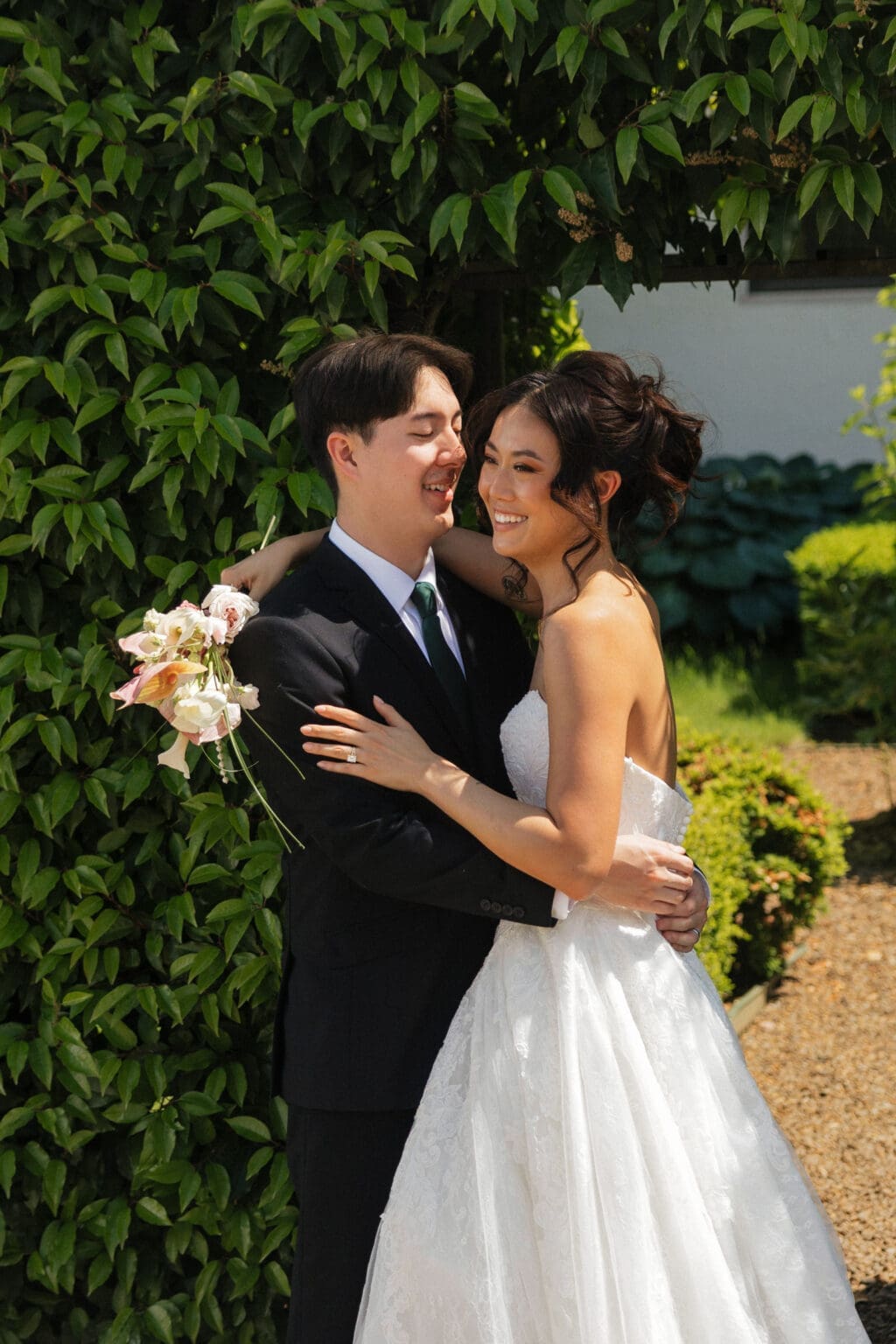 Couple embracing in the gardens at Black Walnut Inn in Dundee, Oregon with lush greenery behind them.